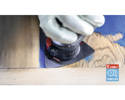 Muž v rukaviciach používa brúsny nástroj na kuse dreva na odstránenie farby. Logo Bosch.