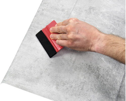 Ruka s raklou nanáša fóliu s kamenným vzorom