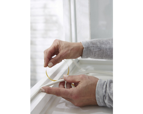 Aplikácia tesniacej pásky na okenný rám na izoláciu.