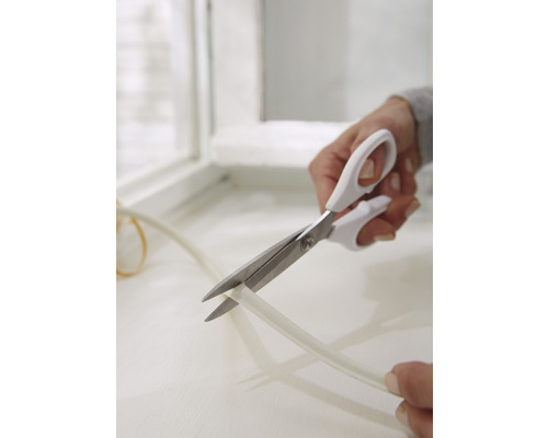 Osoba strihá tesniacu pásku nožnicami.