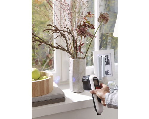 Osoba meria teplotu na okne pomocou infračerveného teplomera od spoločnosti Black and Decker