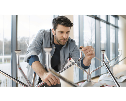 Muž montuje stôl s kovovými nohami a chráničmi podlahy