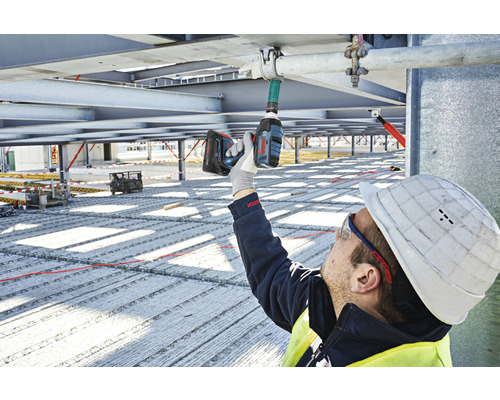 Stavebný robotník používa akumulátorový rázový uťahovák na stavenisku.