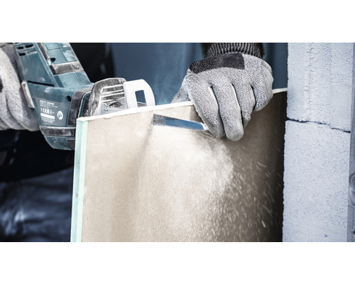 Osoba reže sadrokartónovú dosku pílou.