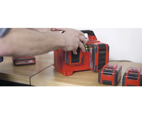 Nabíjačka batérií s viacerými batériami na drevenom stole.