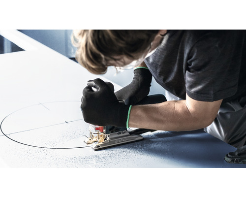 Osoba vyrezáva kruh do dosky pomocou priamočiarej píly.