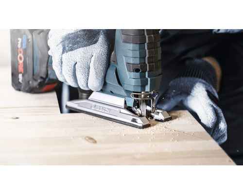 Osoba reže drevo priamočiarou pílou a má na sebe rukavice