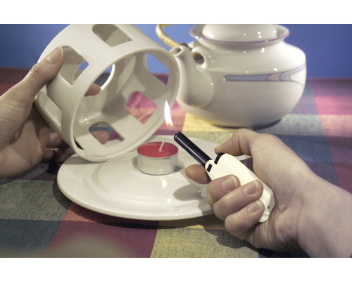 Zapaľovanie čajovej sviečky pod ohrievačom čaju pomocou zapaľovača.