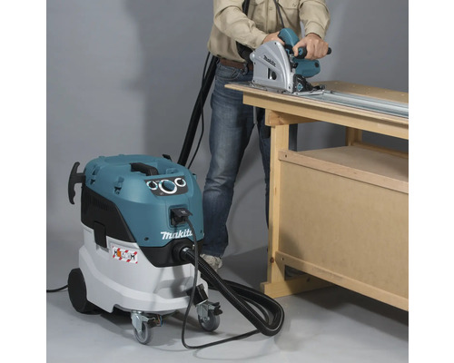 Scéna s osobou používajúcou ručnú kotúčovú pílu v kombinácii s priemyselným vysávačom