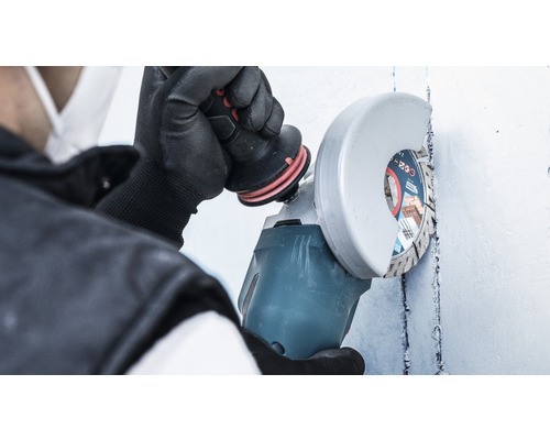 Osoba používa uhlovú brúsku na stene.