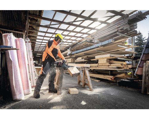 Muž pília drevo akumulátorovou pílou vonku.