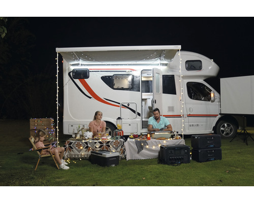 Rodina si užíva kempingovú dovolenku pred obytným vozidlom so svetelnými reťazami a solárnym generátorom