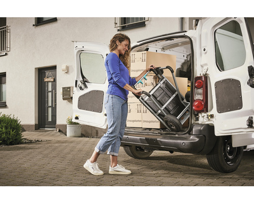 Žena nakladá sťahovacie krabice do dodávky pomocou rudla.