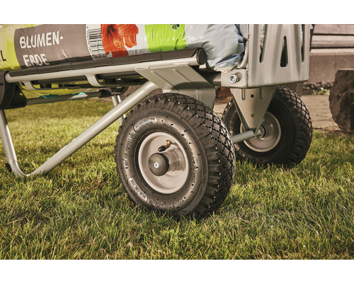 Detailný pohľad na transportný vozík s kvetinovou zeminou na trávniku.