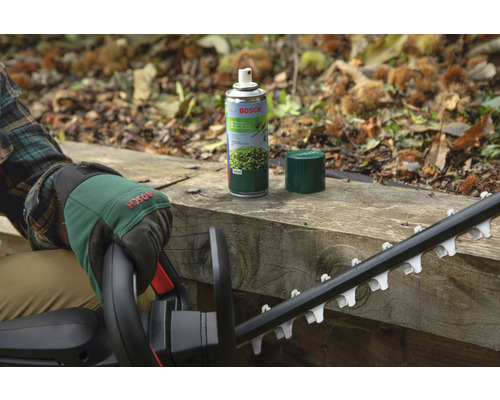 Logo Bosch. Osoba so záhradnými rukavicami a nožnicami na živý plot vedľa spreja na údržbu nožníc na živý plot na drevenom povrchu.