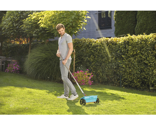 Muž používa rozmetadlo hnojív na trávniku.