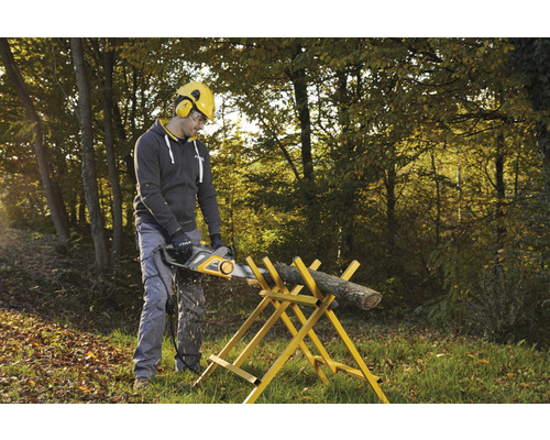 Muž pília kus dreva elektrickou pílou na kozlici