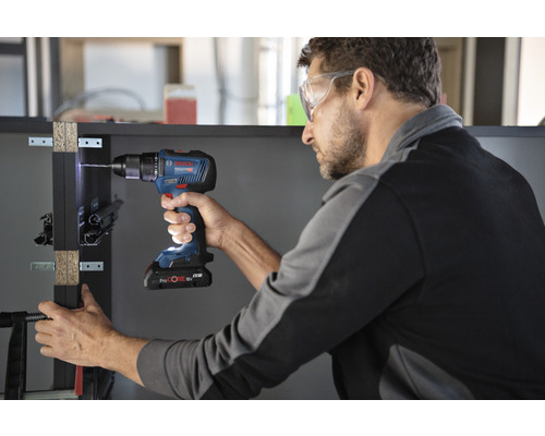 Muž vŕta obrobok pomocou akumulátorového skrutkovača Bosch.