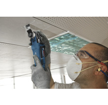 Remeselník pracuje s multifunkčným nástrojom na stropnej doske