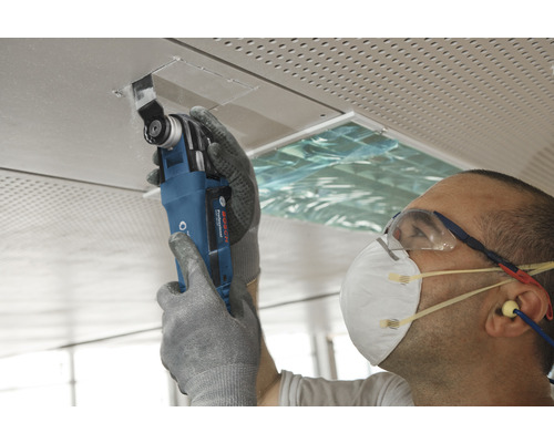 Remeselník pracuje s multifunkčným nástrojom na stropnej doske