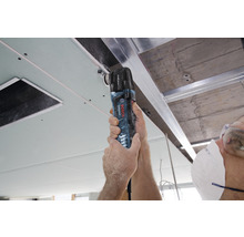 Remeselník používa multifunkčný nástroj Bosch Professional na úpravu stropného panelu.