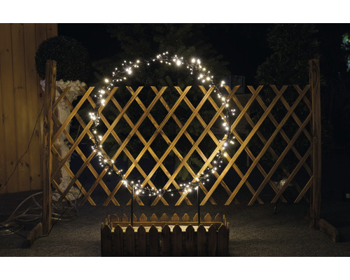 Drevený plot so svetelným oblúkom a kvetináčom v záhrade