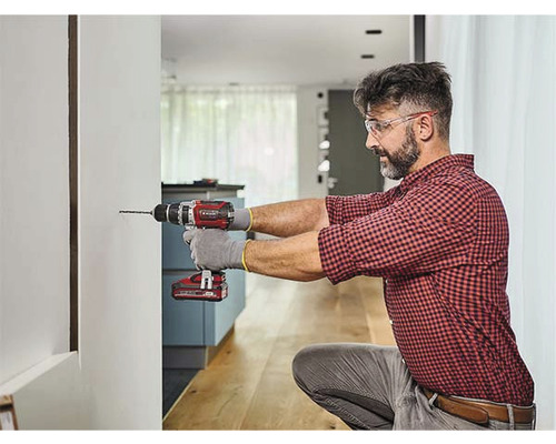 Muž vŕta vŕtačkou dieru do steny.