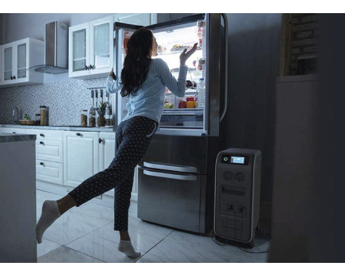 Žena stojí pred chladničkou vedľa generátora prúdu v kuchyni.