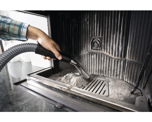 Osoba vysáva popol z krbu pomocou vysávača popola