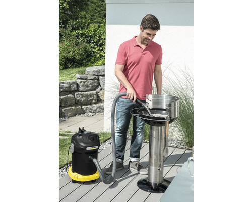 Muž čistí gril na drevené uhlie s vysávačom popola vonku