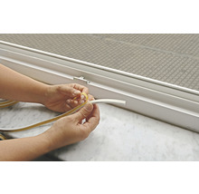 Osoba odstraňuje ochrannú fóliu z okenného tesniaceho pásu