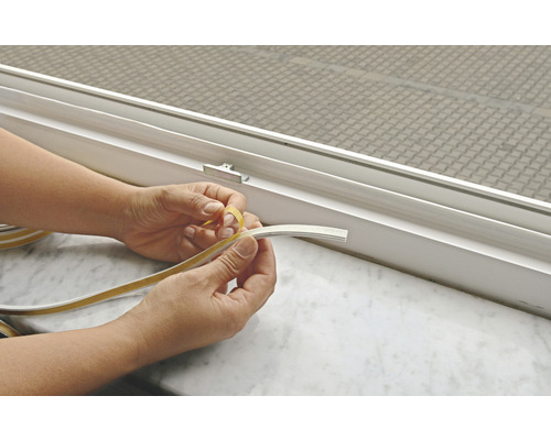 Osoba odstraňuje ochrannú fóliu z okenné tesniacej pásky