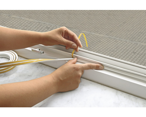 Osoba pripevňuje tesniacu pásku na rám okna.