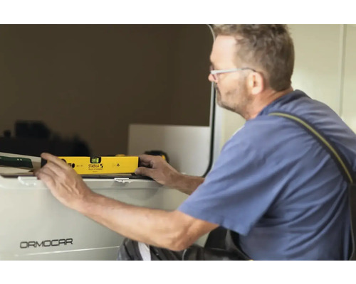 Muž používa vodováhu na vyrovnanie.