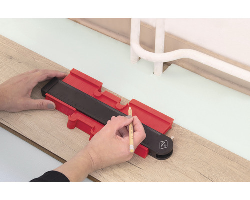 Osoba používa obrysovú šablónu na orýsovanie na drevenej podlahe