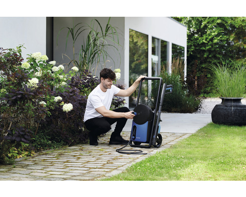 Muž pripája vysokotlakový čistič v záhrade.