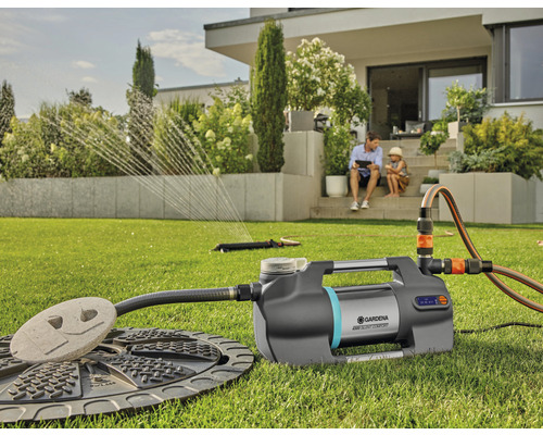 Domáca vodáreň Gardena s príslušenstvom v záhrade, zatiaľ čo otec a dieťa sedia na terase