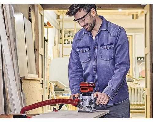 Muž v dielni používa hornú frézku na prácu s drevom.