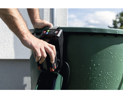 Muž vkladá batériu do čerpadla dažďovej nádrže.