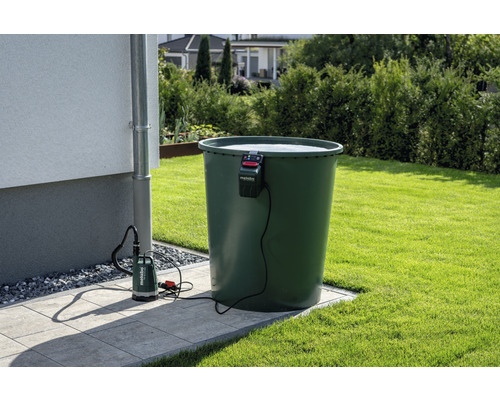 Záhradná scéna s nádržou na dažďovú vodu, stenou domu, odkvapovou rúrou a ponorným čerpadlom s logom Metabo