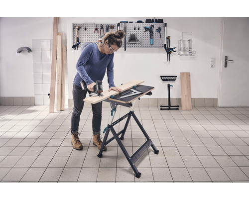 Žena reže drevo na pracovnom stole pomocou priamočiarej píly v dielni