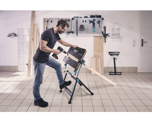 Muž vŕta akumulátorovou vŕtačkou obrobok na pracovnom stole Wolfcraft Master 600.