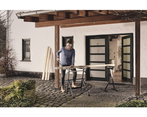 Žena reže drevo na skladacom pracovnom stole vonku.