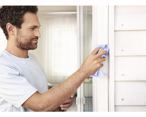 Muž čistí rám okna handrou