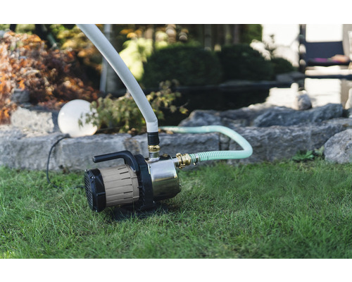 Záhrada so záhradným čerpadlom a zavlažovacou hadicou na trávniku