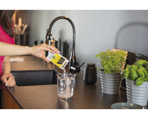 Žena vlieva čistiaci prostriedok Kärcher do odmerky s vodou.