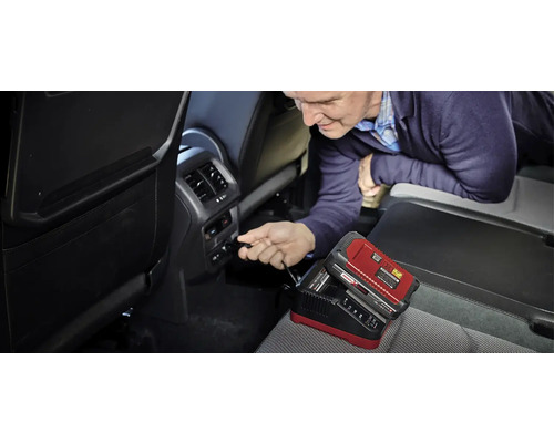 Muž pripája nabíjačku autobatérií v aute