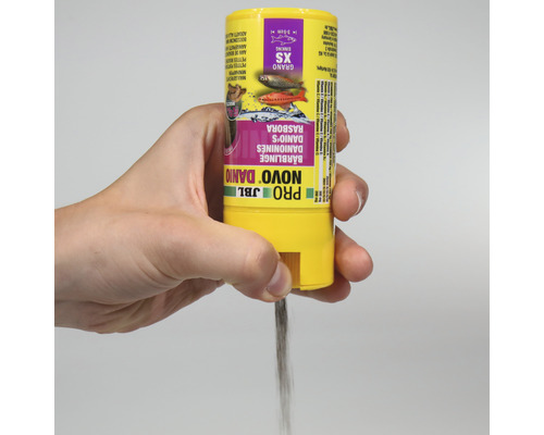 Ruka drží krmivo JBL Novo Danio pre malé ryby