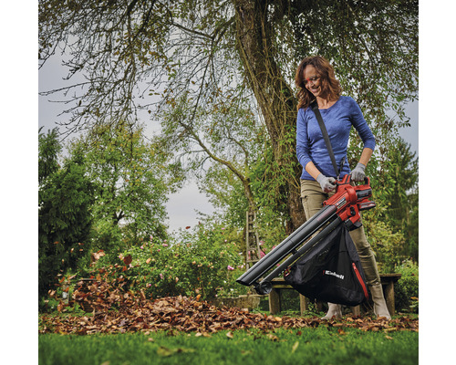 Žena používa vysávač lístia v záhrade na odstránenie lístia.