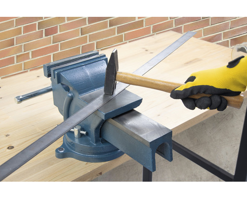 Pracovný stôl so zverákom, kladivom a kusom kovu